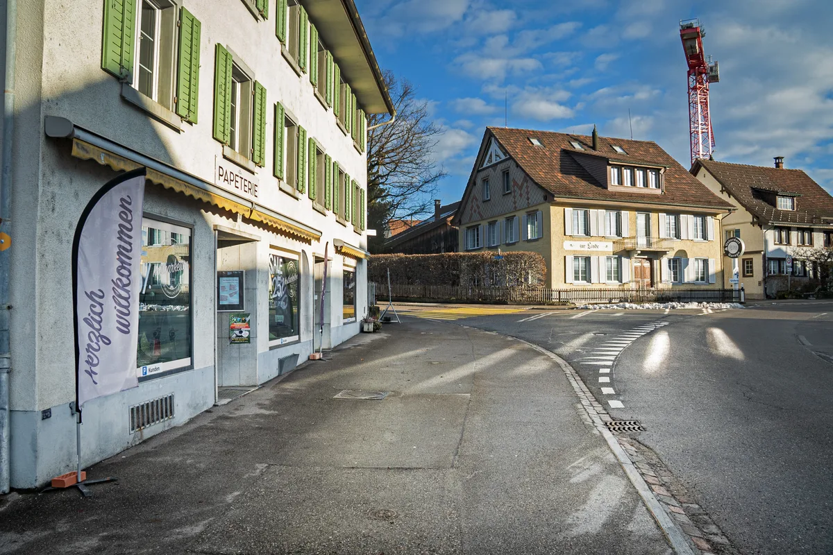 Ein Haus mit einem Ladenlokal im Erdgeschoss an einer Strassenverzweigung.